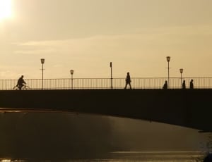 silhouette of bridge and people walking into it during daytime thumbnail