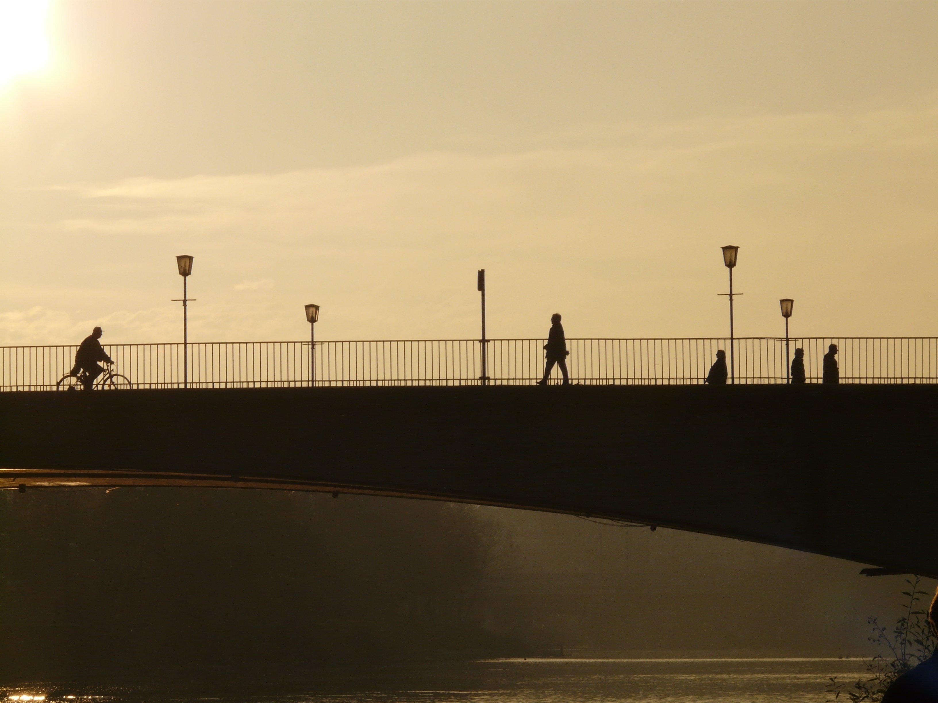 silhouette of bridge and people walking into it during daytime