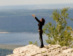 women in black long sleeves and pants standing on white rock formation thumbnail