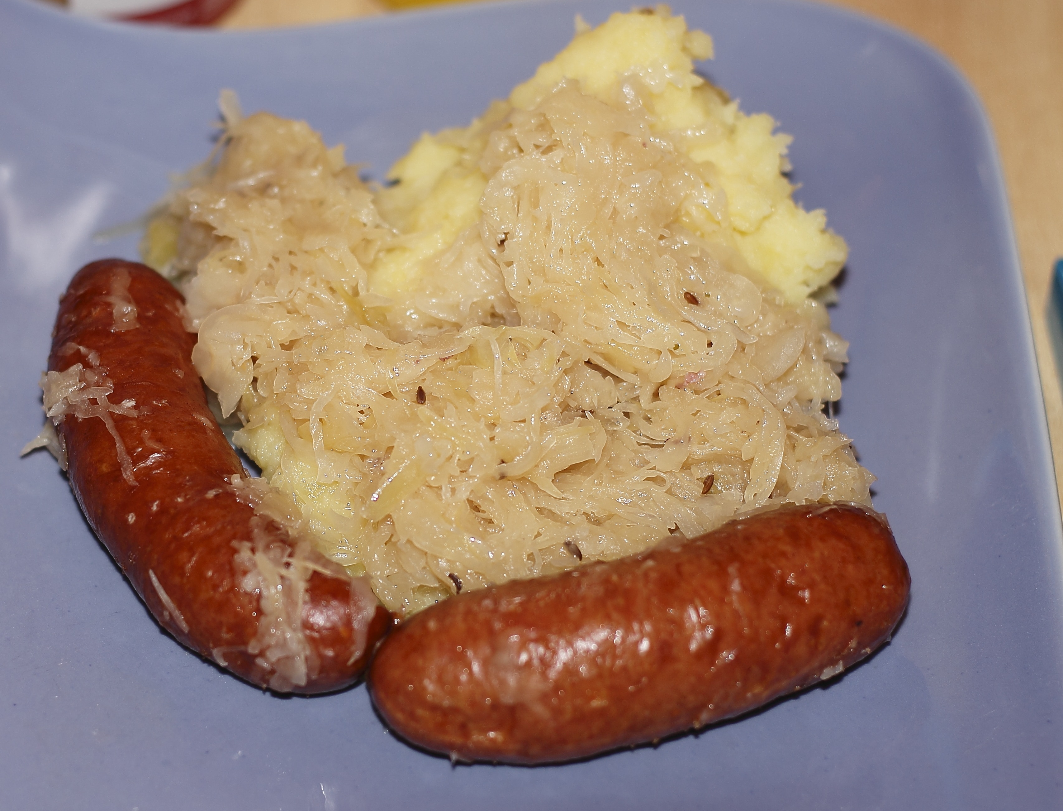 2 sausages with mash potato on purple ceramic square plate