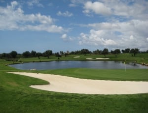 gold course under white and blue cloudy sky thumbnail
