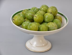 green fruits on white ceramic footed bowl thumbnail