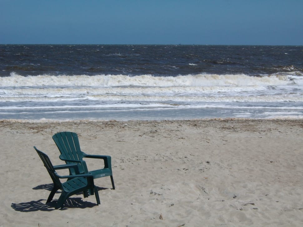 2 dark green plastic armchairs on gray sand near seashore preview
