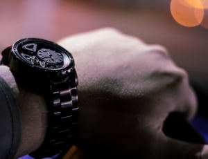 human hand wearing black chronograph watch with link bracelet thumbnail