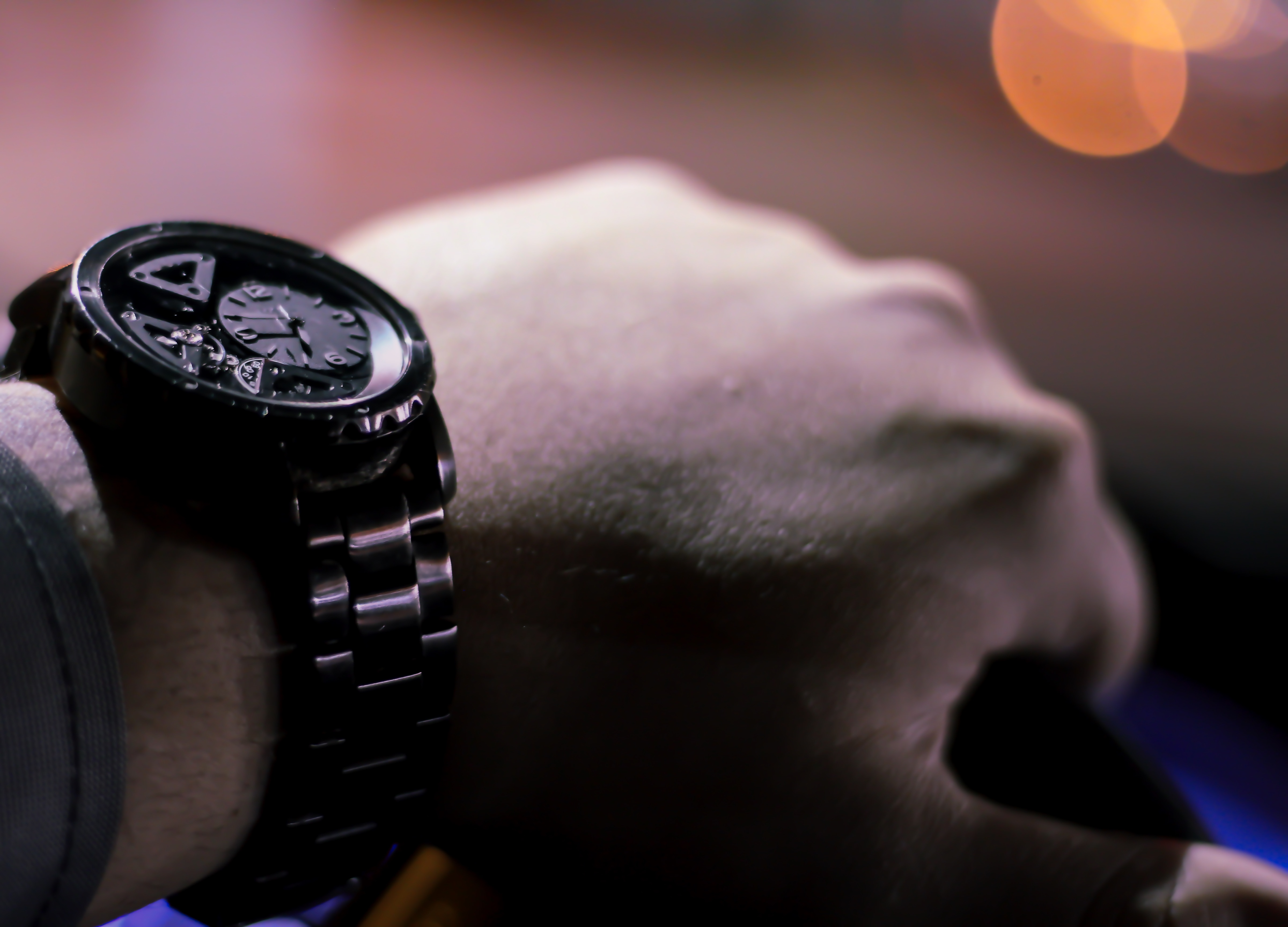 human hand wearing black chronograph watch with link bracelet