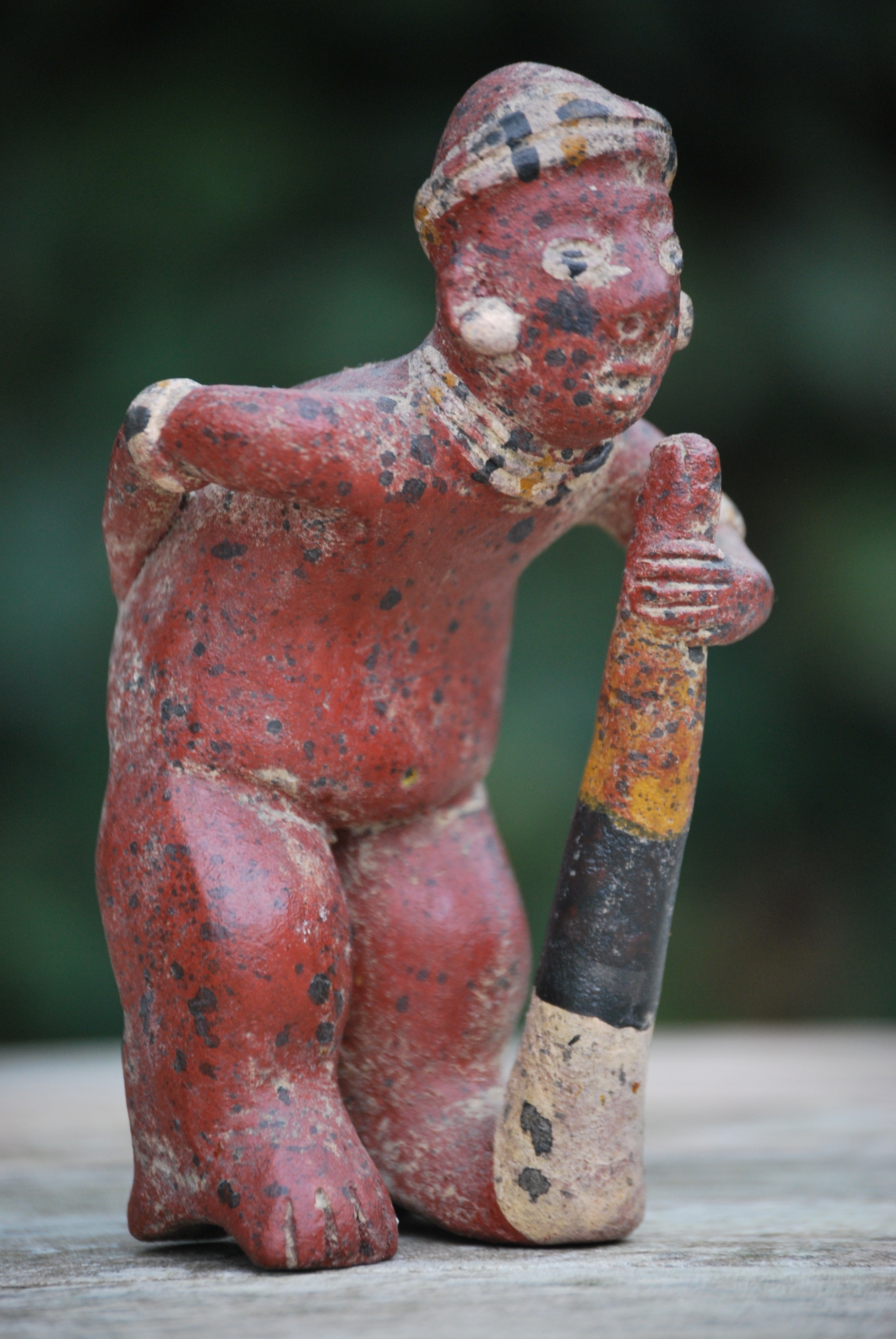 red tribal man bending figurine