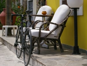 road bicycle beside armchair on sidewalk during daytime thumbnail