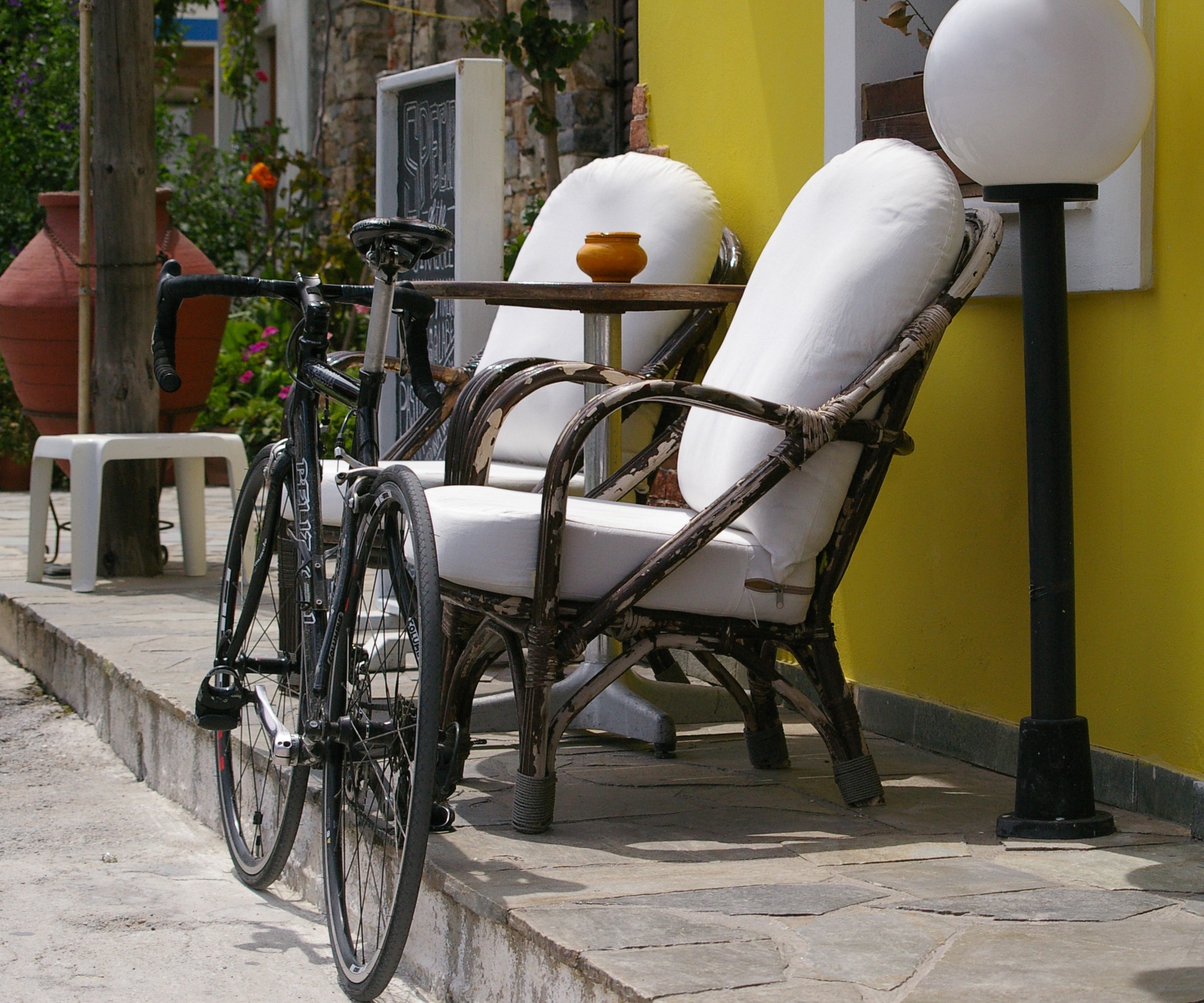 road bicycle beside armchair on sidewalk during daytime