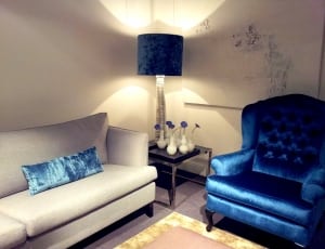 black shade clear glass base table lamp and beige sofa and blue satin tufted sofa chair thumbnail