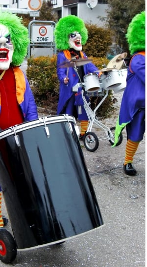 group of people in clown masks playing percussion instruments on gray concrete road thumbnail