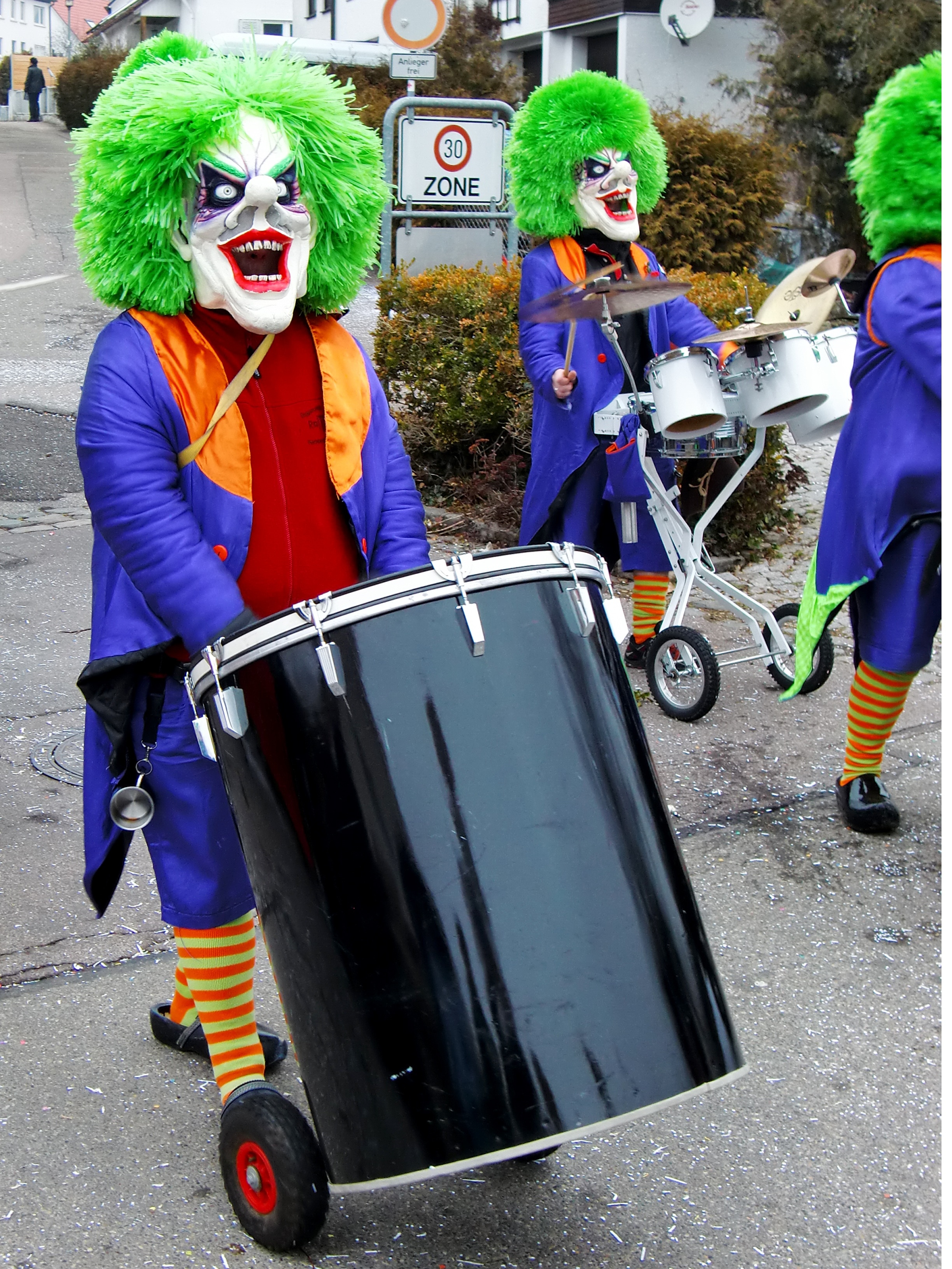 group of people in clown masks playing percussion instruments on gray concrete road