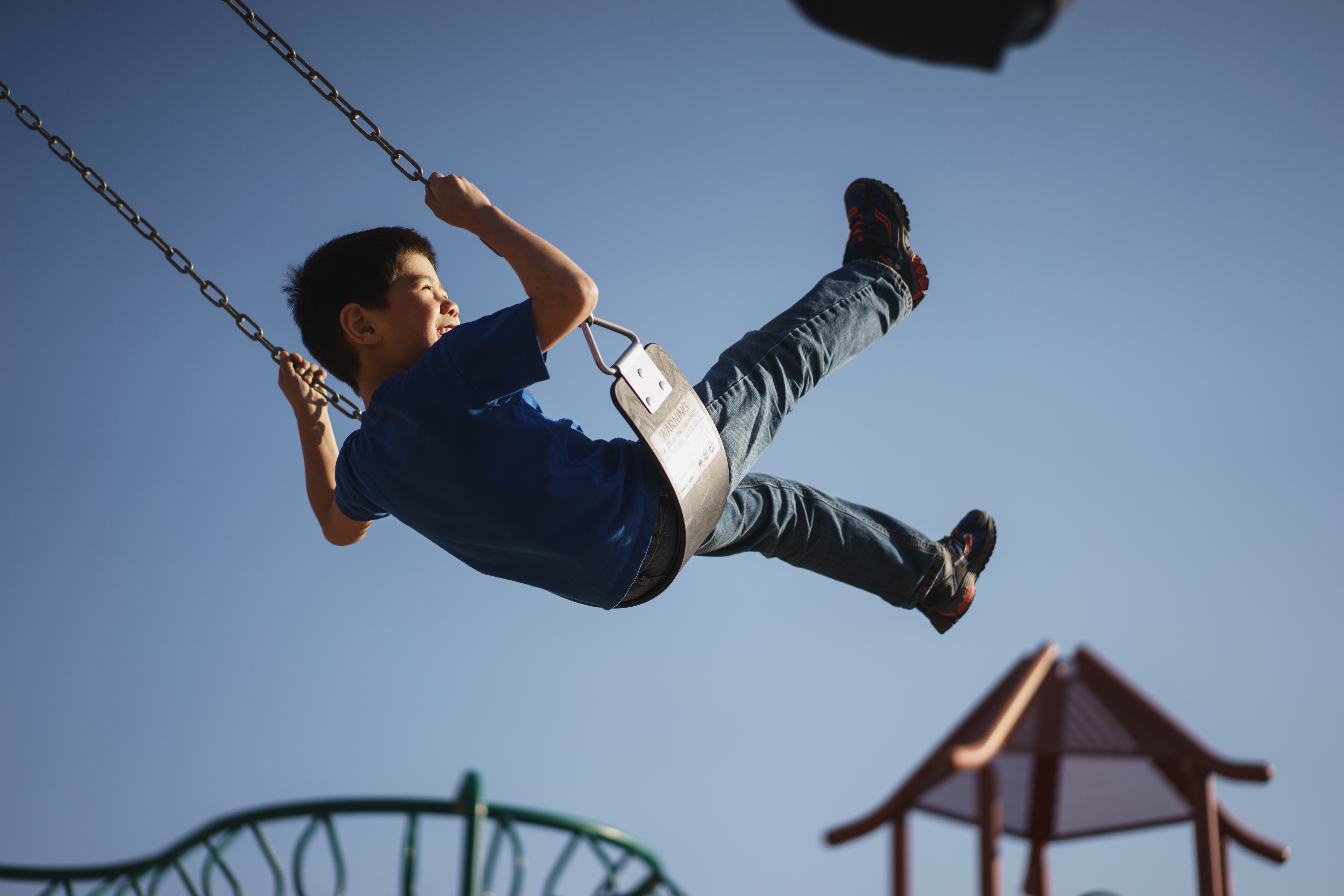 boy in blue t-shirt and blue denim pants outfit on swing