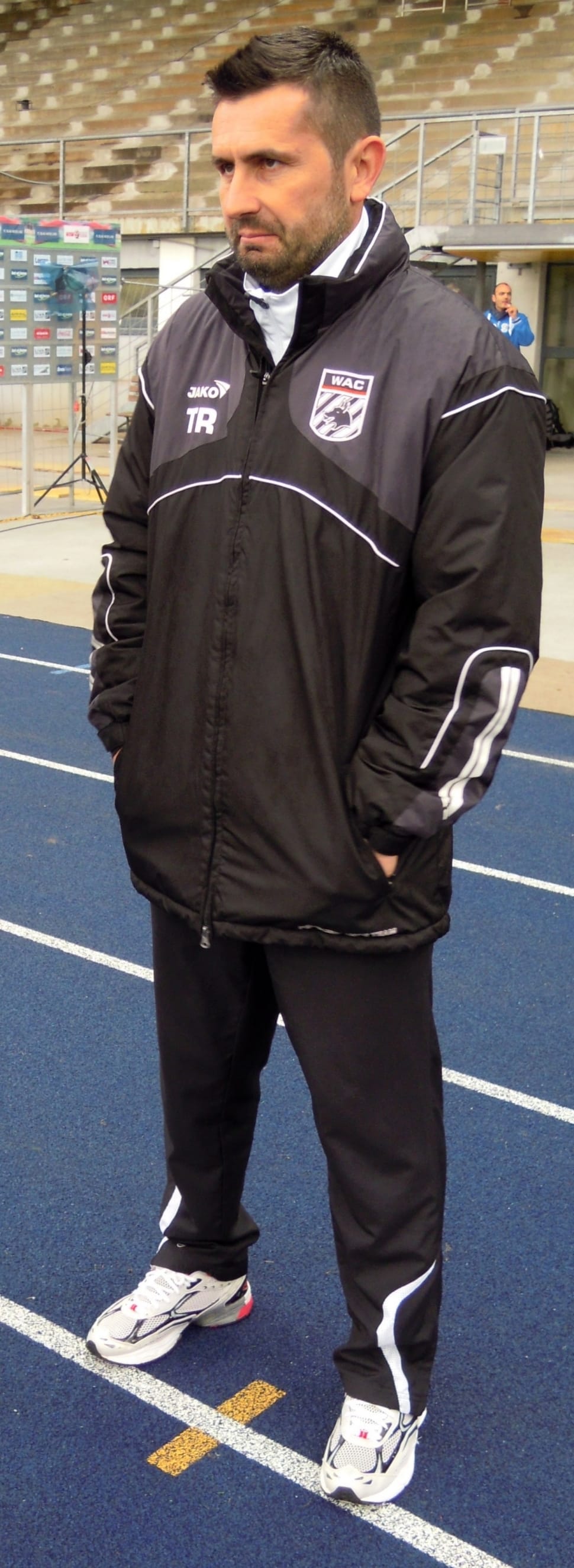man's black zip up jacket with black pants and white and black running shoes preview