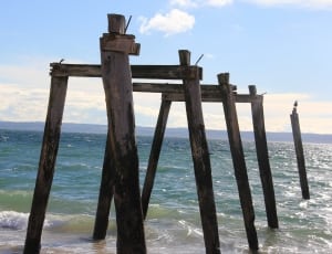 brown wooden dock stand on body of water during daytime thumbnail