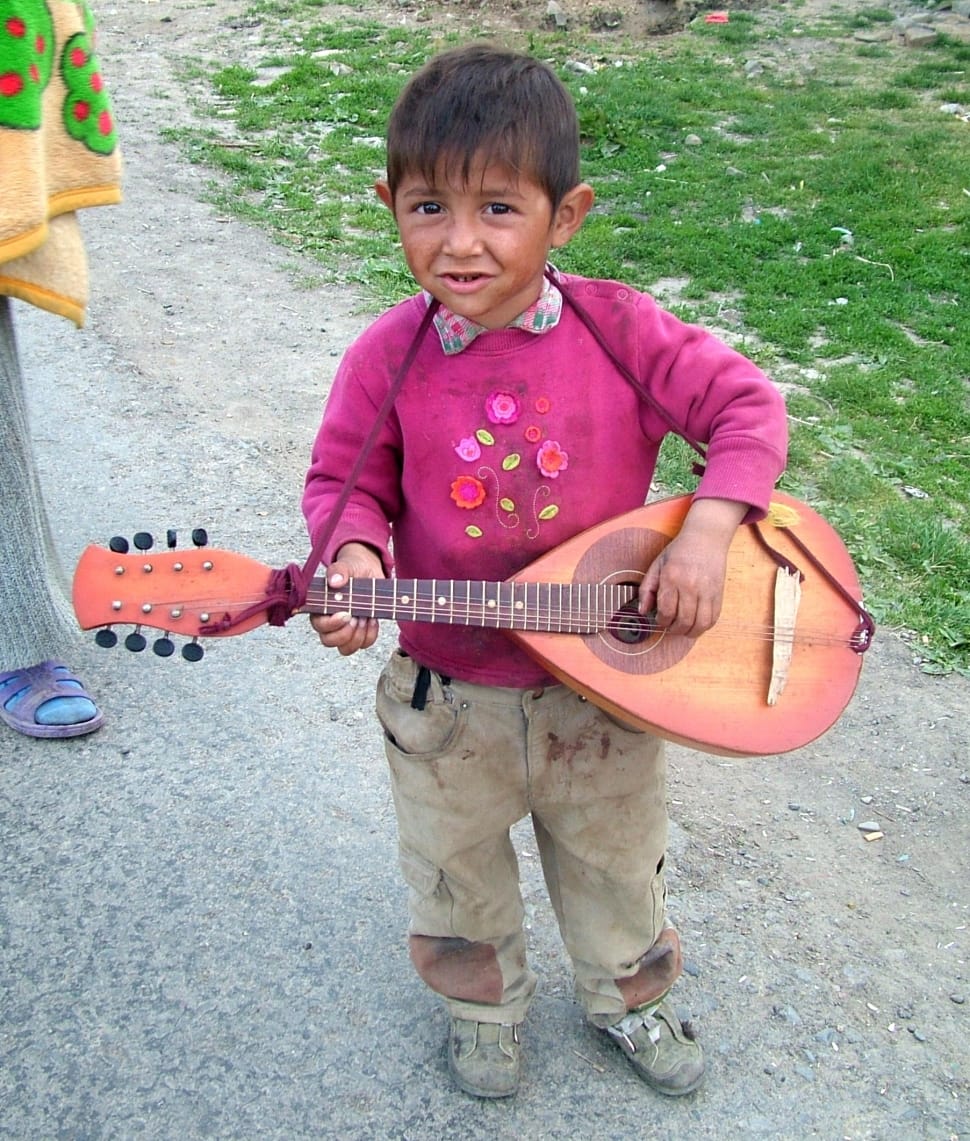 boy's pink floral collared sweater,brown cargo pants,gray shoes and brown string instrument preview