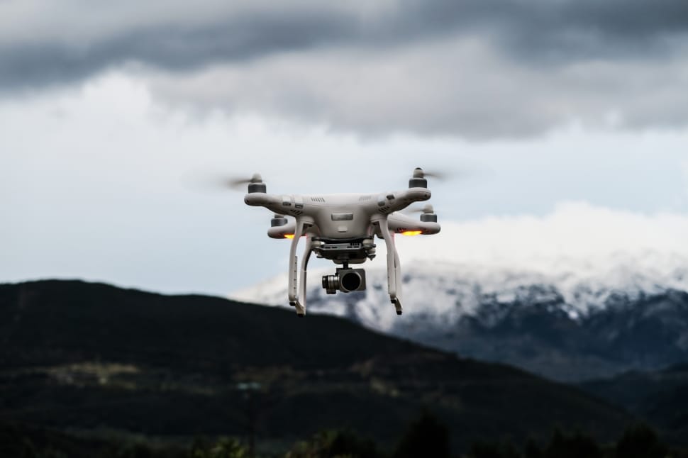 white quadcoper drone with black action camera under white cloud and blue sky during daytime preview