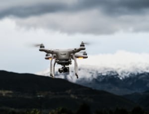 white quadcoper drone with black action camera under white cloud and blue sky during daytime thumbnail