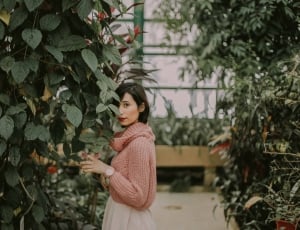 woman wearing pink knitted long sleeve top near green plants thumbnail