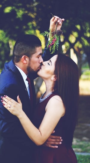 man holding mistletoe kissing woman thumbnail