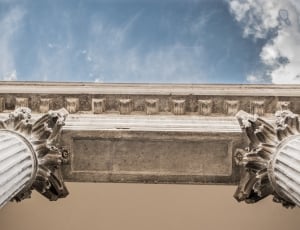 worm's eye view photography of grey columns under blue cloudy sky during daytime thumbnail