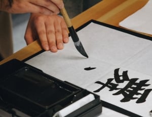 person holding paint brush writing kanji text thumbnail