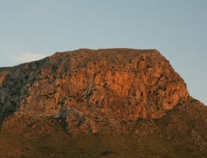 photograph of a brown rock mountain during sunset thumbnail