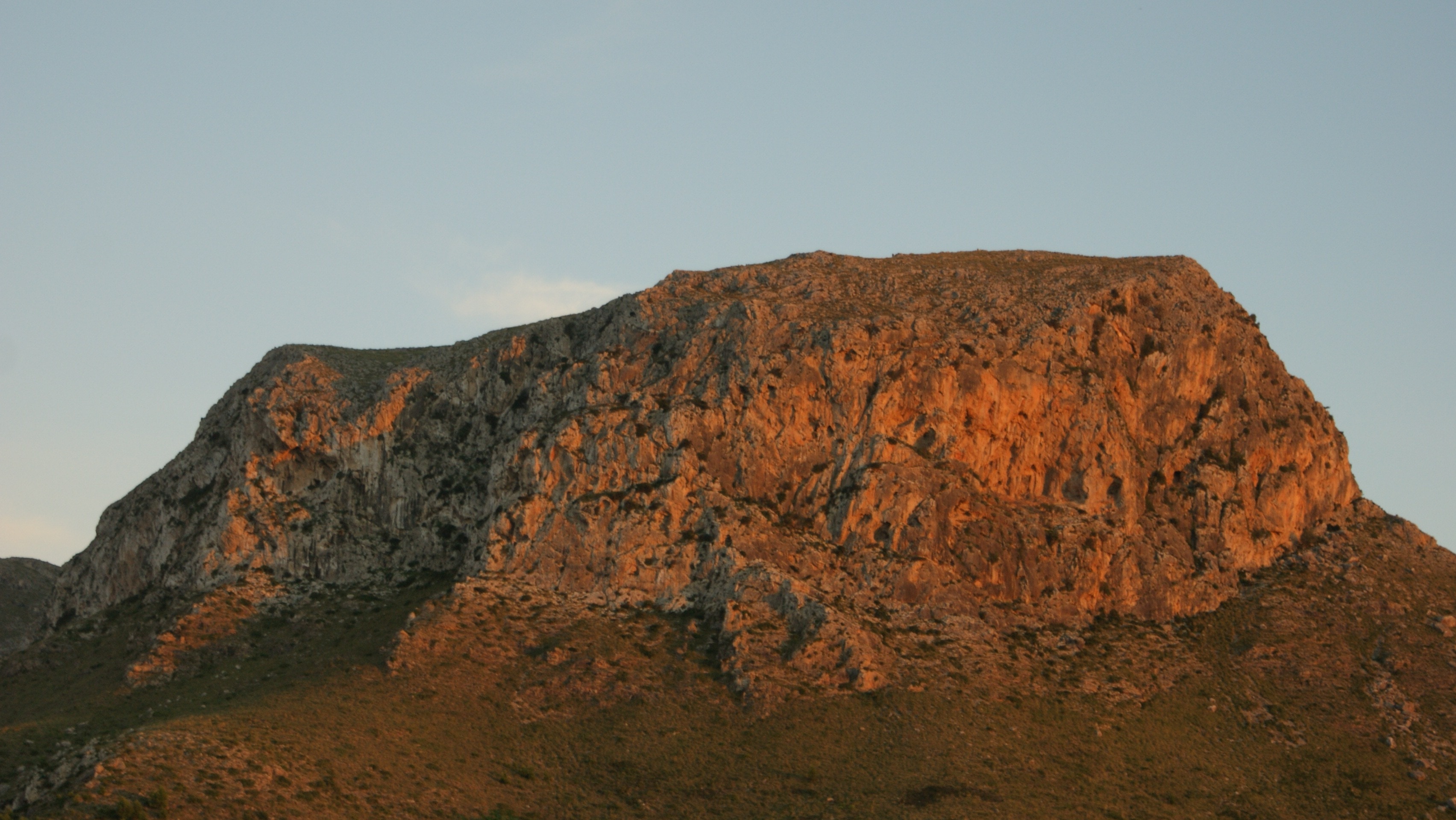 photograph of a brown rock mountain during sunset
