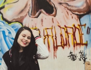woman in black and white letterman jacket with a skull graffiti background thumbnail