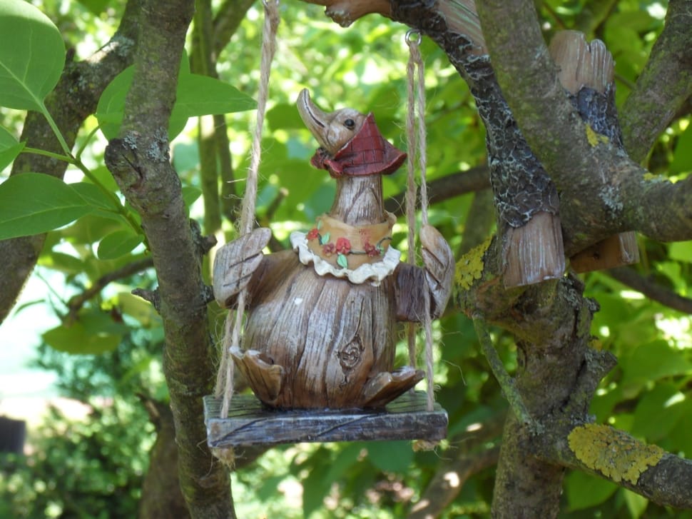 brown wooden goose sitting on swing ornament preview