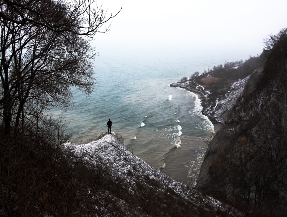 person on mountain peak watching ocean water view during daytime photo preview