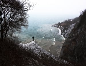 person on mountain peak watching ocean water view during daytime photo thumbnail