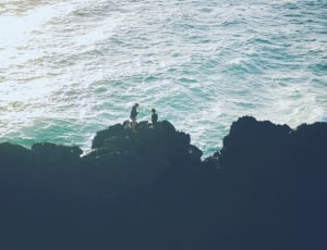 two person on rock cliff beside body of water during daytime ] thumbnail
