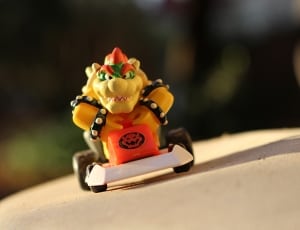 yellow orange and green dragon riding on go kart toy thumbnail