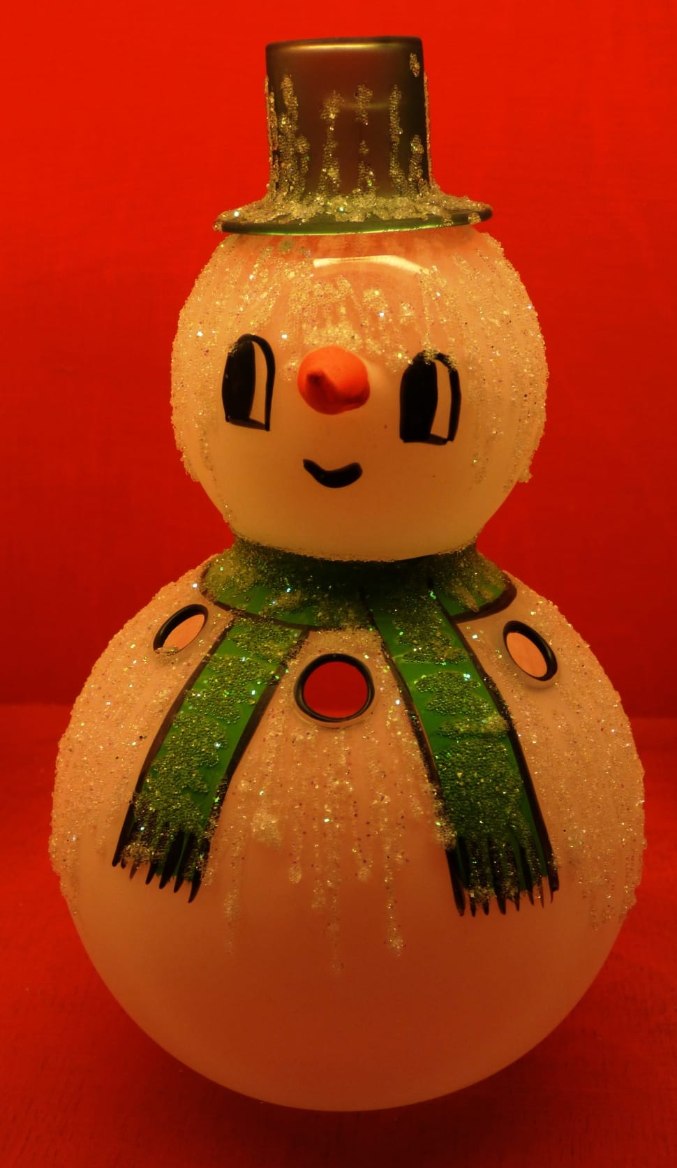 closed up photo of snowman figurine wearing green scarf and hat preview