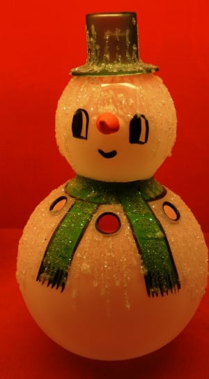 closed up photo of snowman figurine wearing green scarf and hat thumbnail