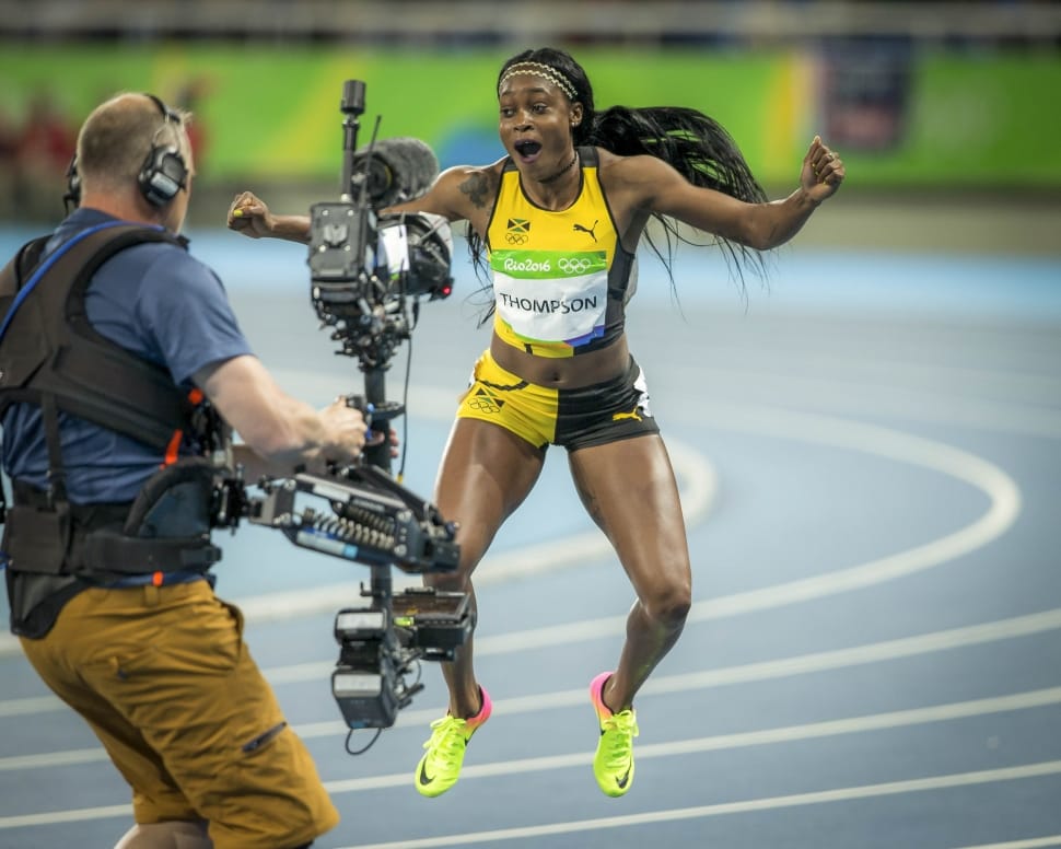 woman in yellow-and-black running gear jumping in front of camera preview