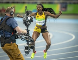 woman in yellow-and-black running gear jumping in front of camera thumbnail