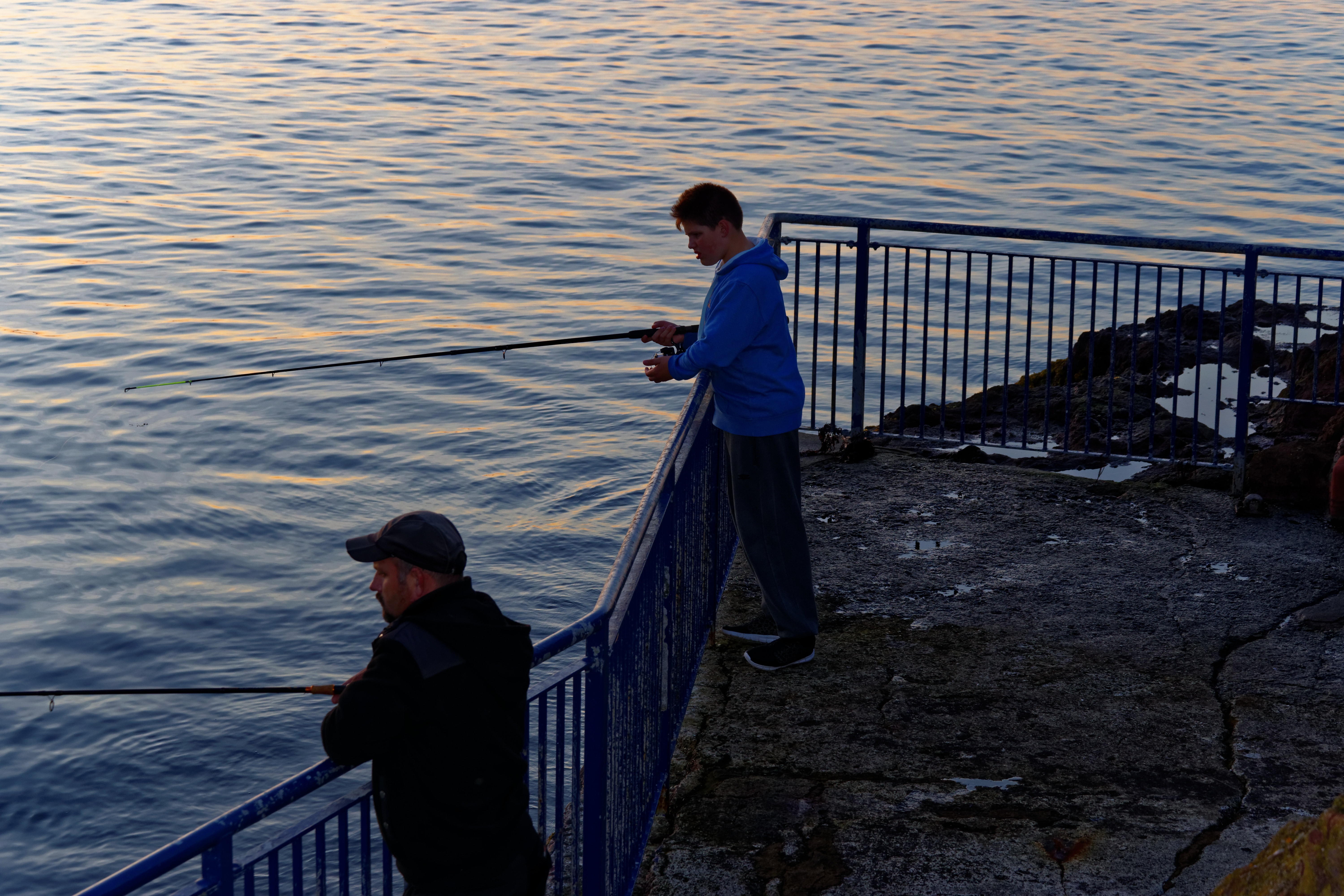 two man in hooded jacket fishing during daytime