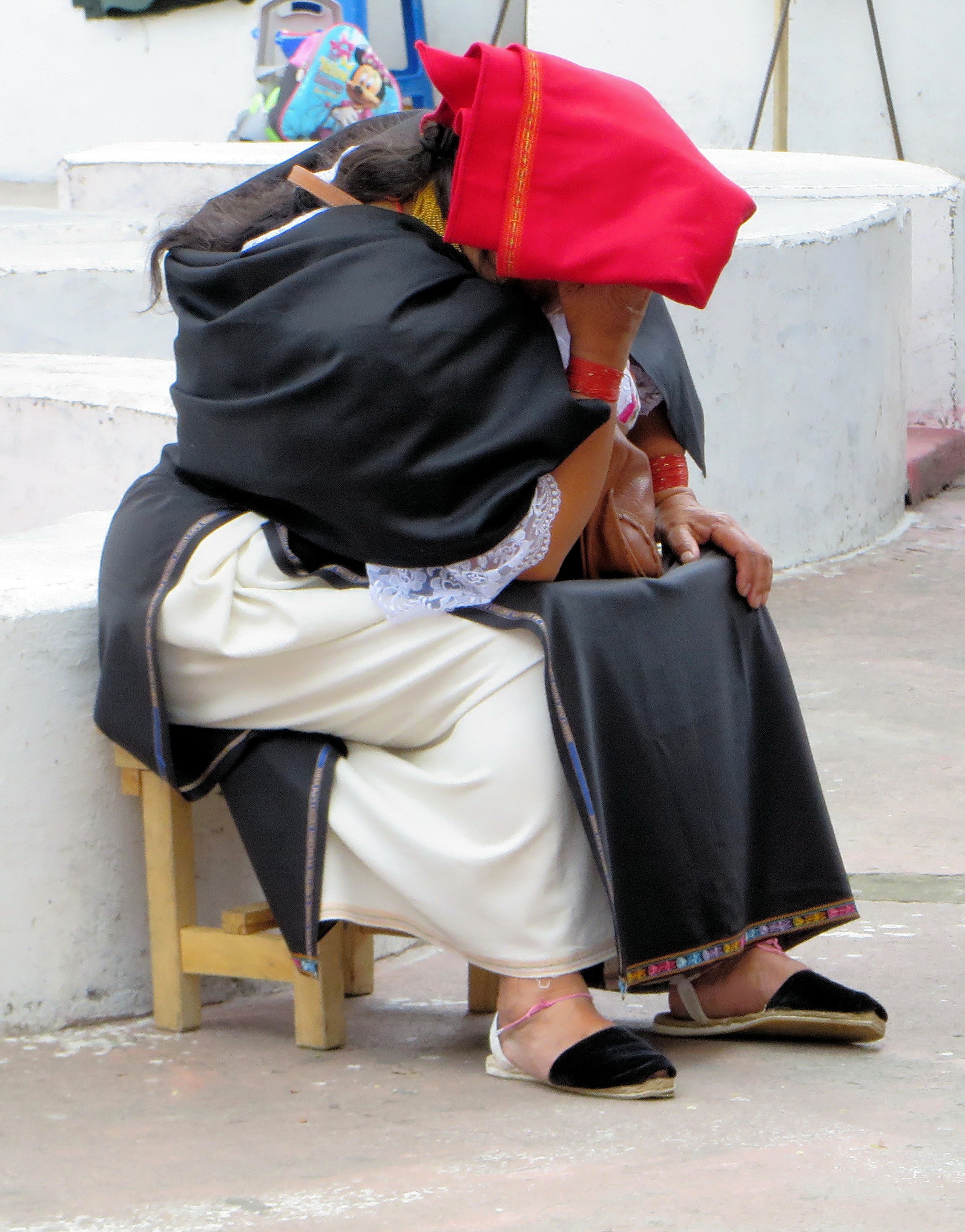 woman in black red and white sari sitting along the road
