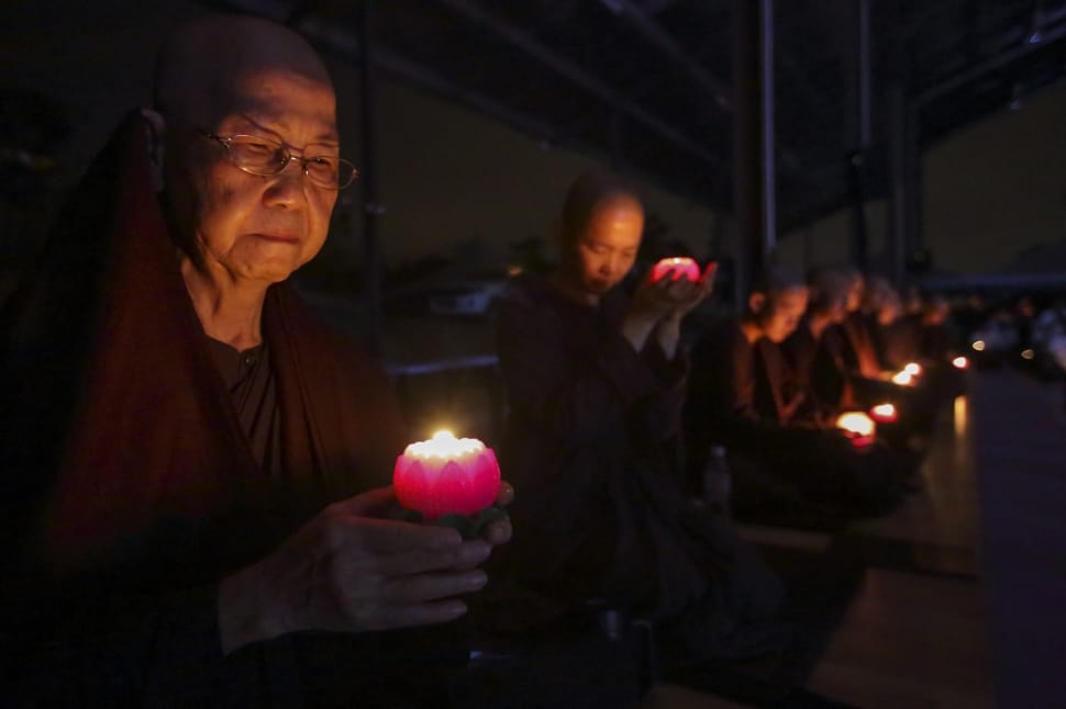 monks holding candles  while sitting down in a line preview