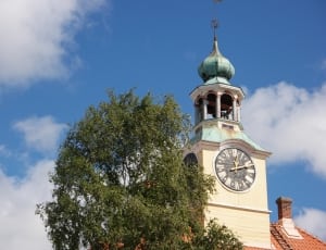 white tower with clock beside green tree thumbnail