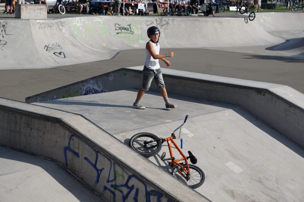 man wearing helmet standing on the middle of ramp his bmx bike on the ground preview