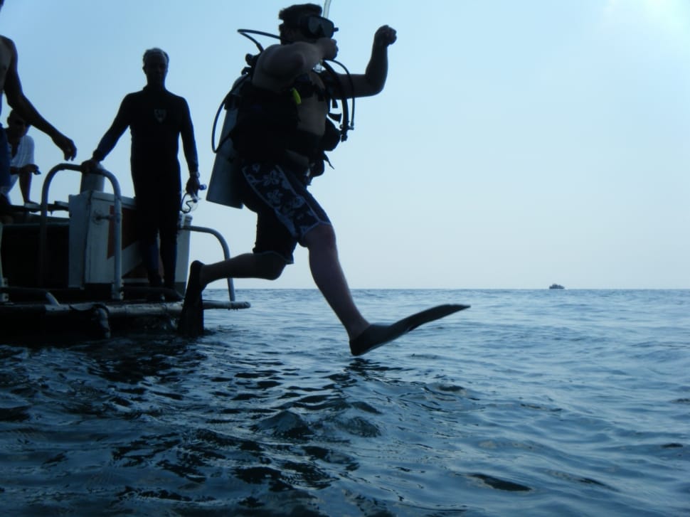person in diving apparel jumping towards sea during daytime preview