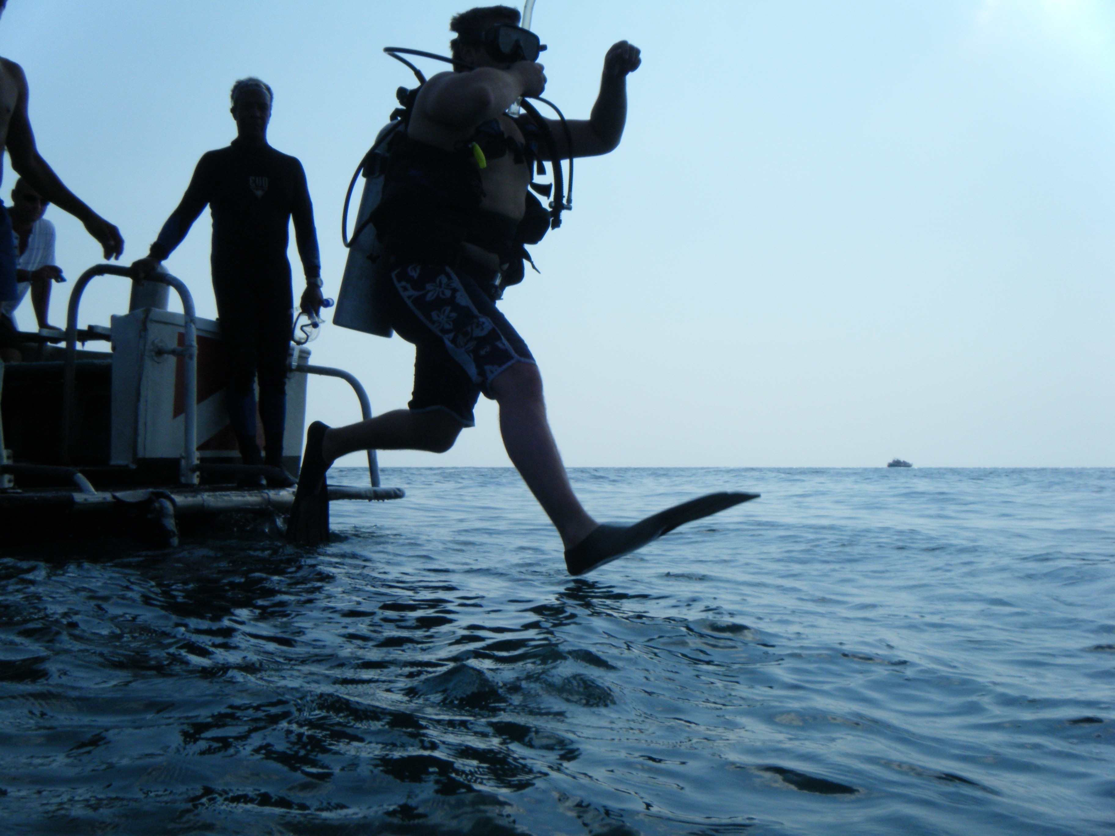 person in diving apparel jumping towards sea during daytime