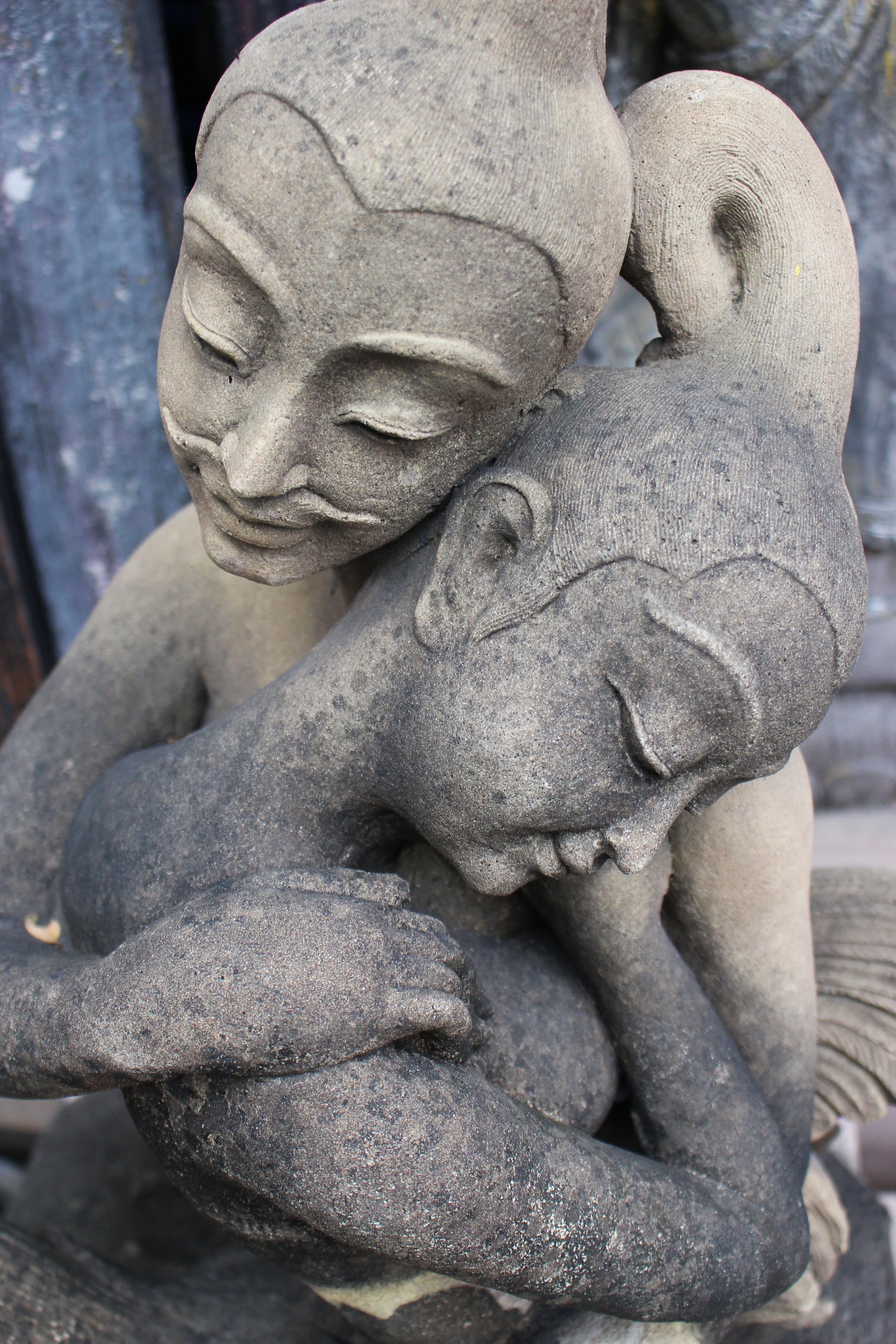 2 women hugging concrete figurine