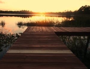 landscape picture of brown wooden bridge during sunset thumbnail