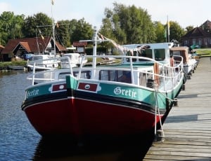green, white, and maroon Bretje boat on a dock thumbnail