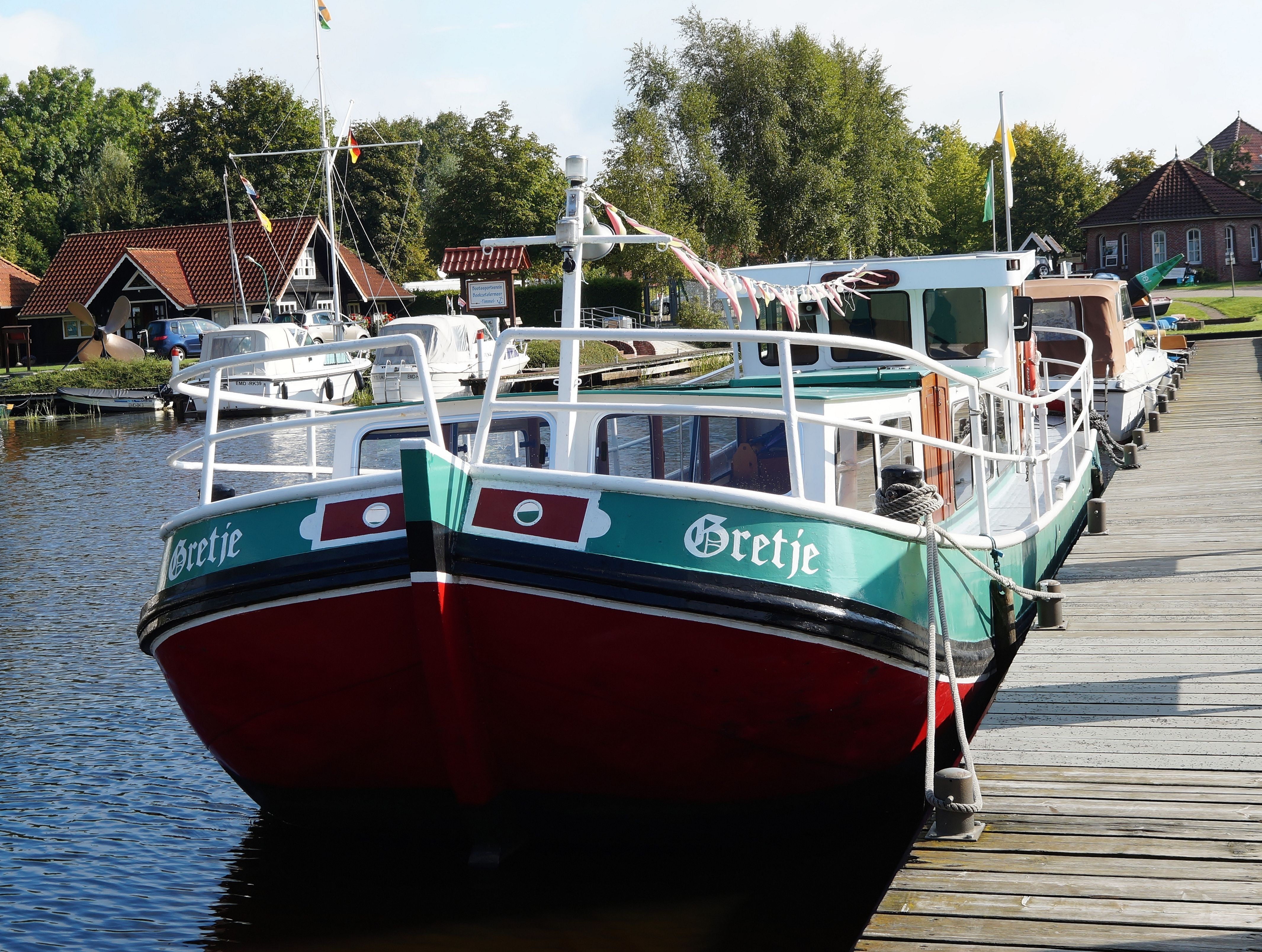 green, white, and maroon Bretje boat on a dock