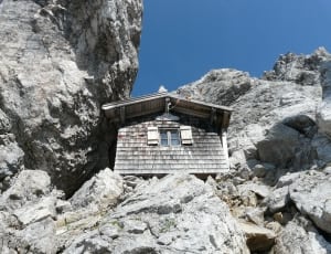 grey wooden house surrounded by concrete rocks thumbnail