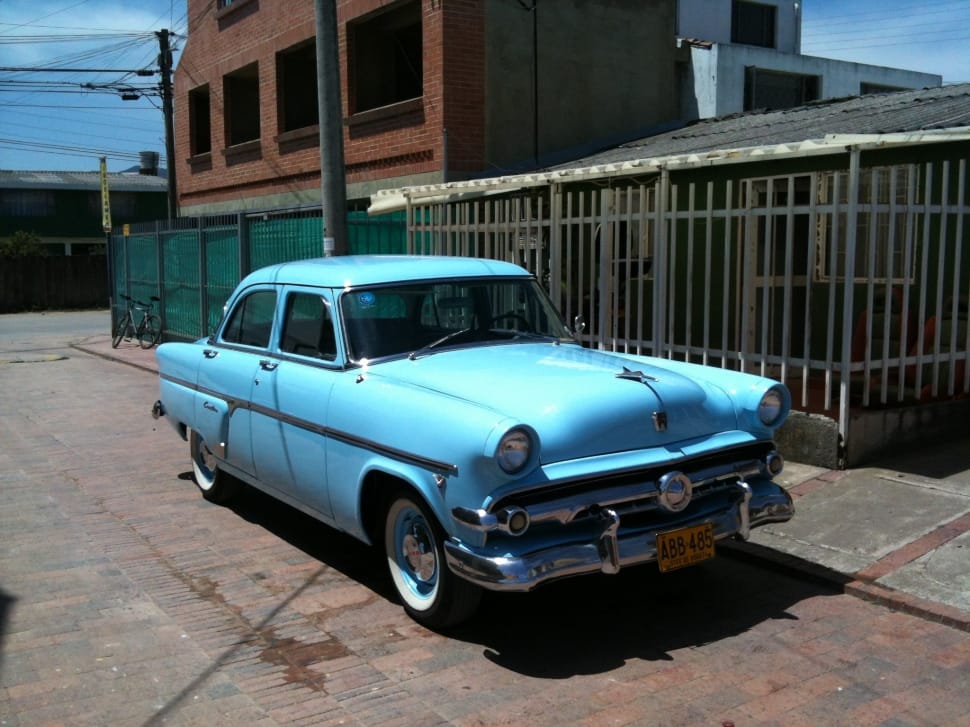 blue classic sedan parked near house during daytime preview